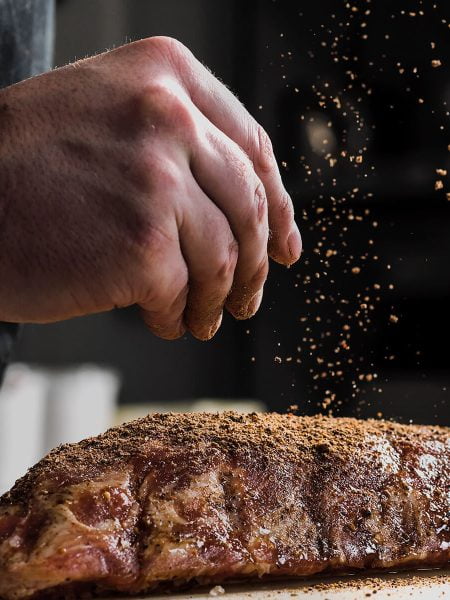 Image of someone adding spices to meat
