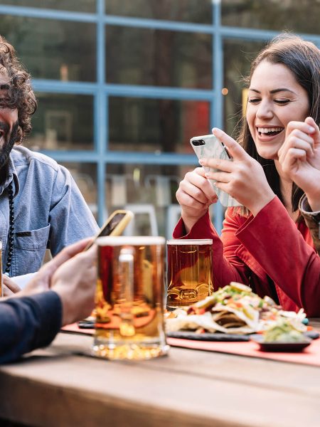 Image of friends laughing, drinking beer and eating nachos